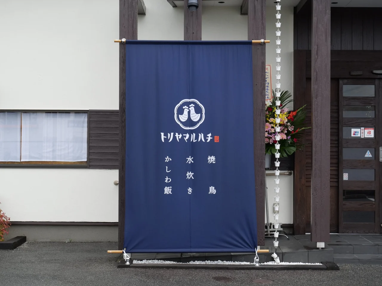 トリヤマルハチの店頭に掲げられた紺色の看板幕