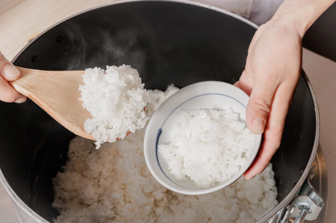 新潟産コシヒカリ イメージ。湯気の立つ炊きたてご飯を茶碗によそう様子
