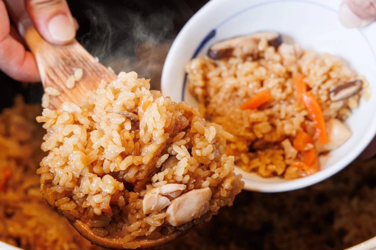 月替わり炊き込み（とり飯）を木べらですくった湯気の立つ炊き込みごはん