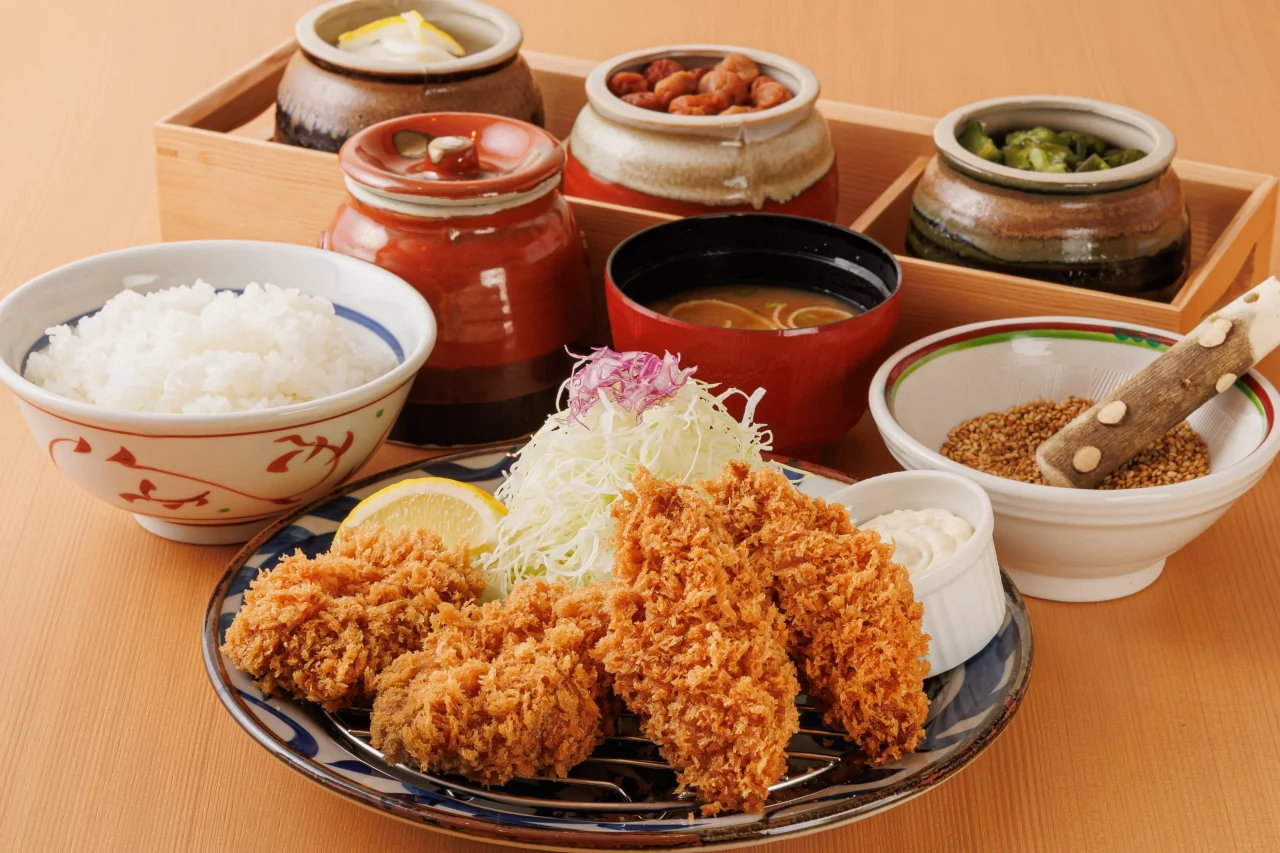 大粒かきフライひれかつ膳。フライの皿にごはん、味噌汁、漬物の壺