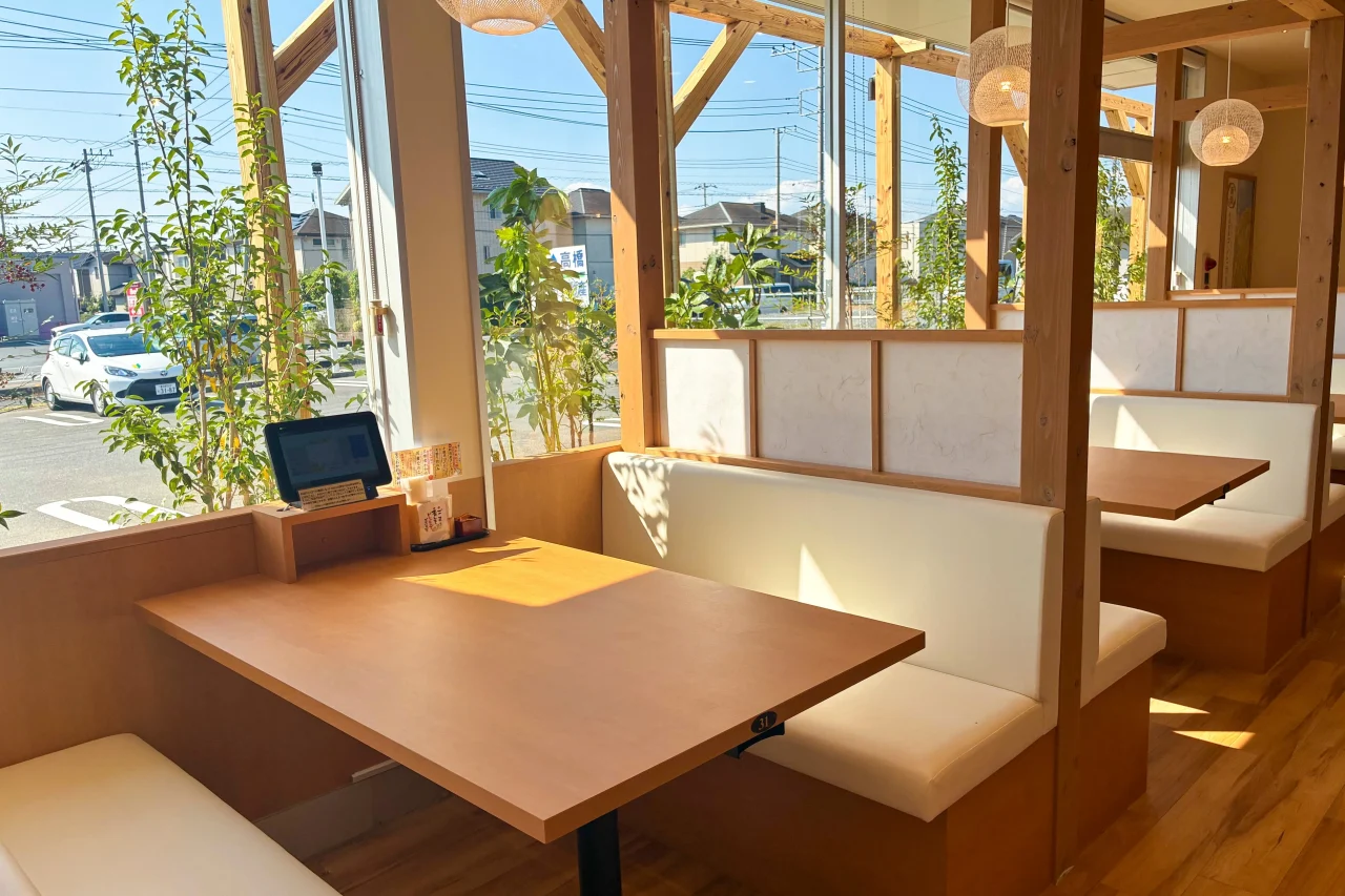 木の柱と大きな窓のある明るい店内のボックス席