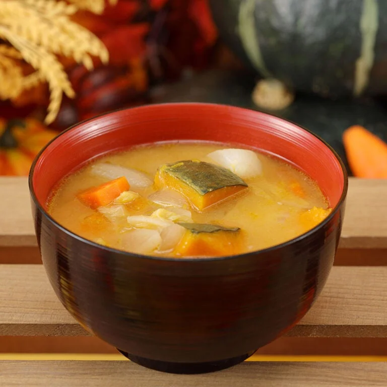 黒と赤の汁椀に入った、かぼちゃなど野菜入りの豚汁