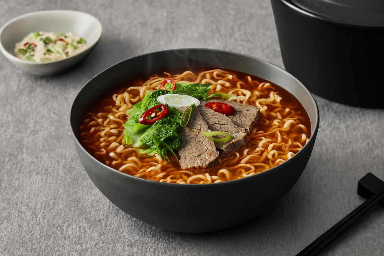 三養1963の調理例。牛肉や白菜、青ねぎ、赤唐辛子をのせた赤いスープの麺