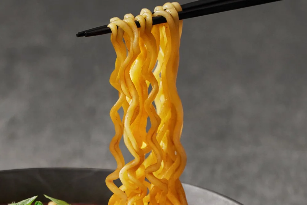 箸で持ち上げた香ばしい麺。黄金色の縮れた麺