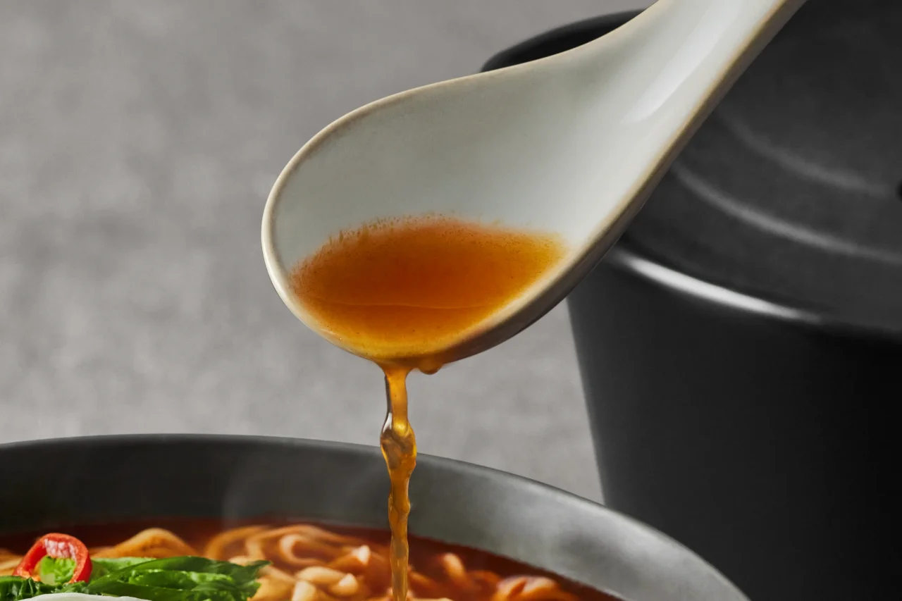 深く濃厚な、ピリ辛スープをすくった白いレンゲと麺入りの器