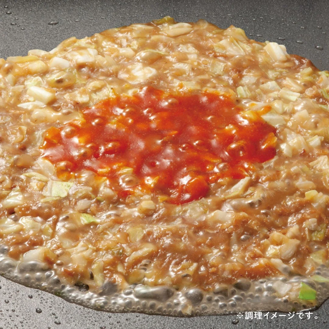 ピリッと旨い明太もんじゃ。鉄板上で円形に広がり中央に赤いソース