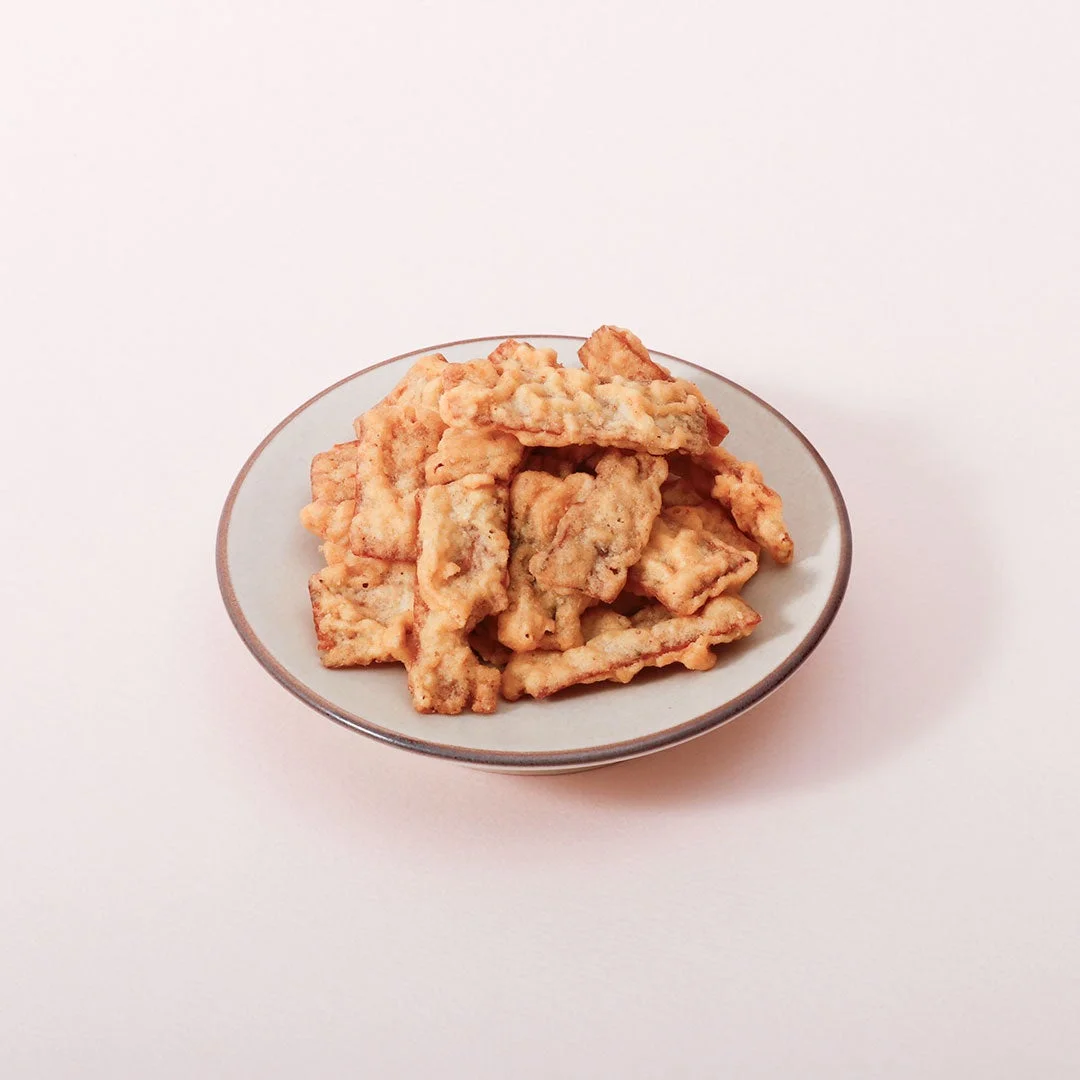明太マヨいか天を丸い皿に盛った、衣をまとった揚げ菓子