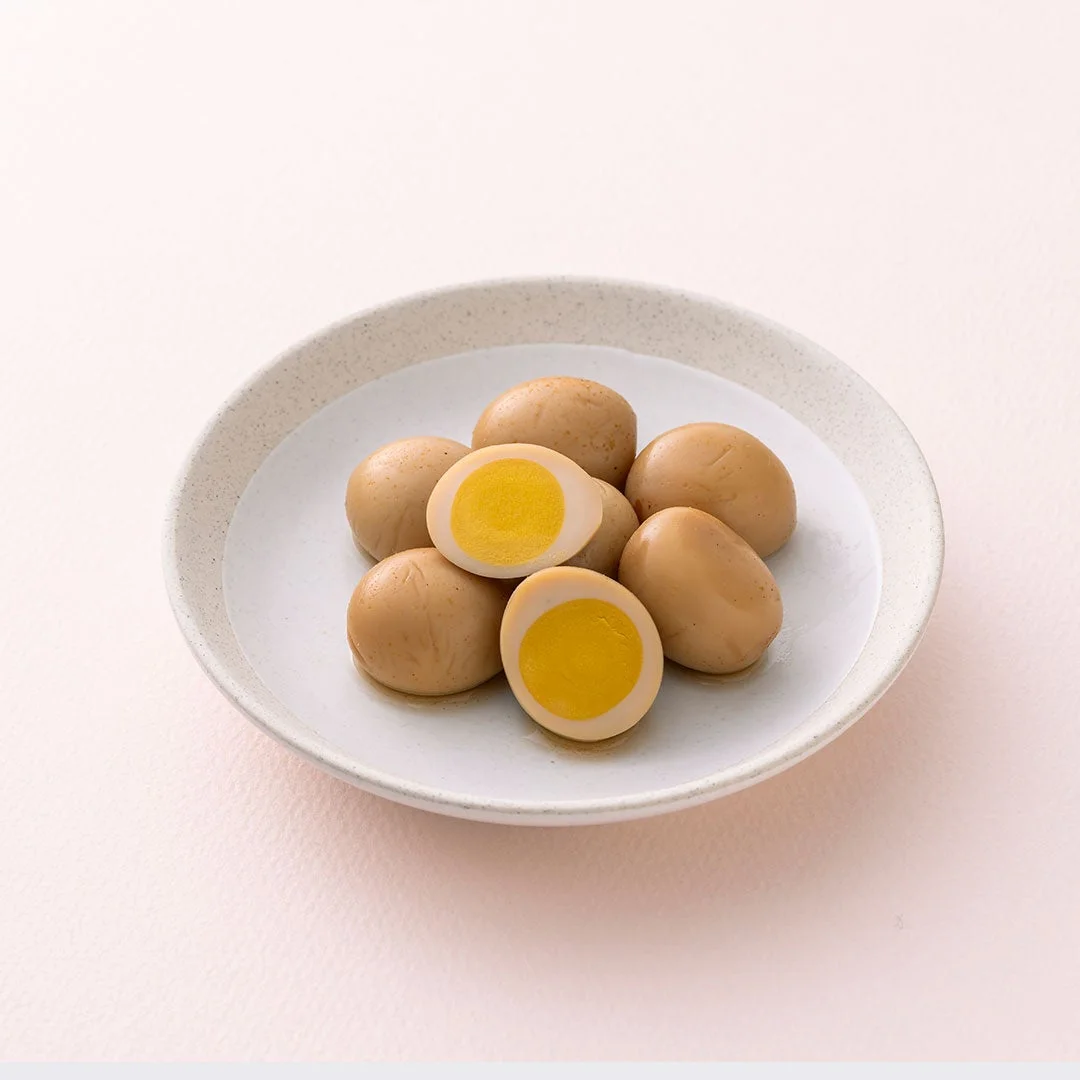 明太うずら。白い皿に盛られた茶色い味付けうずら卵と、半分に切った黄身