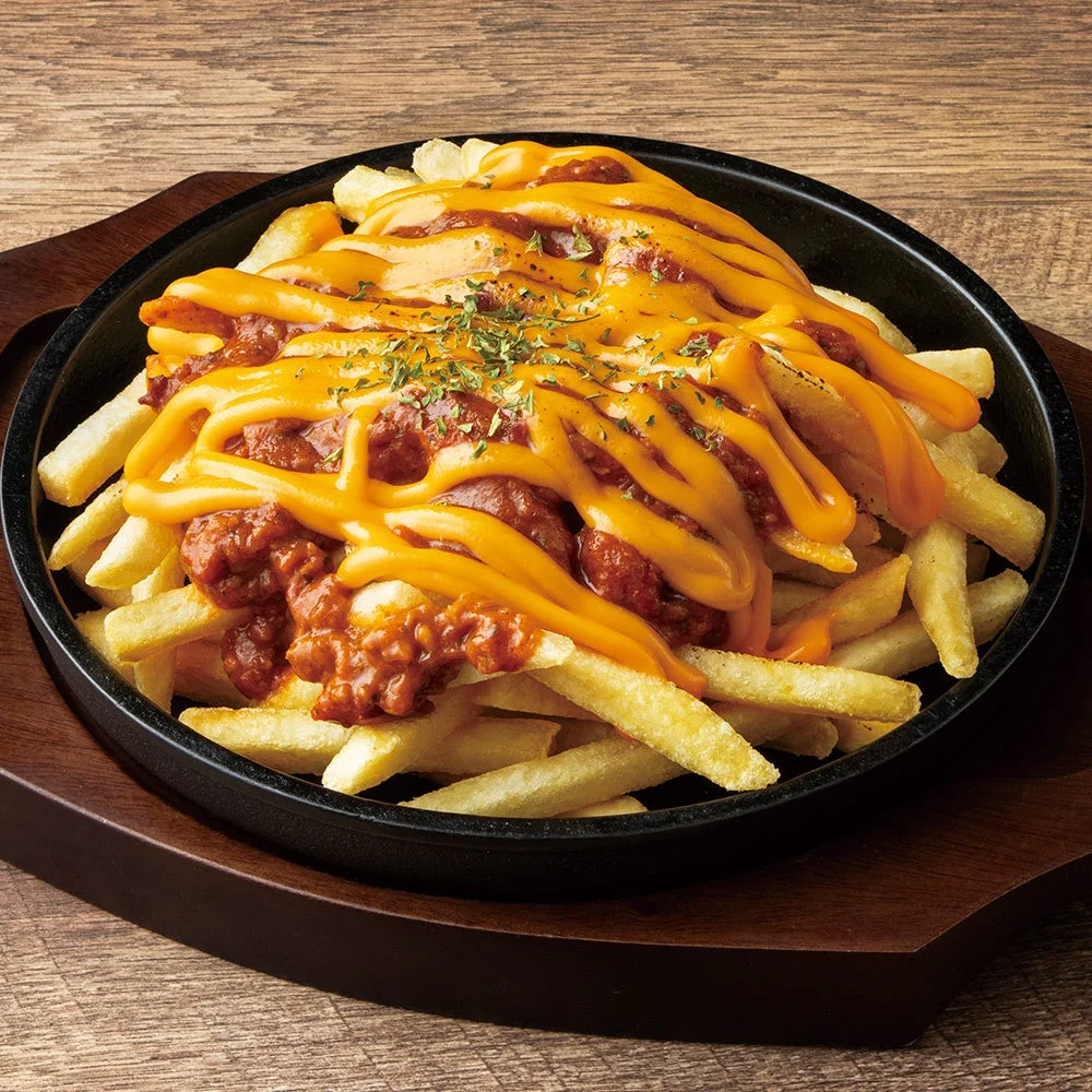 黒い鉄皿にのったフライドポテトにチリとチーズソースをかけた料理