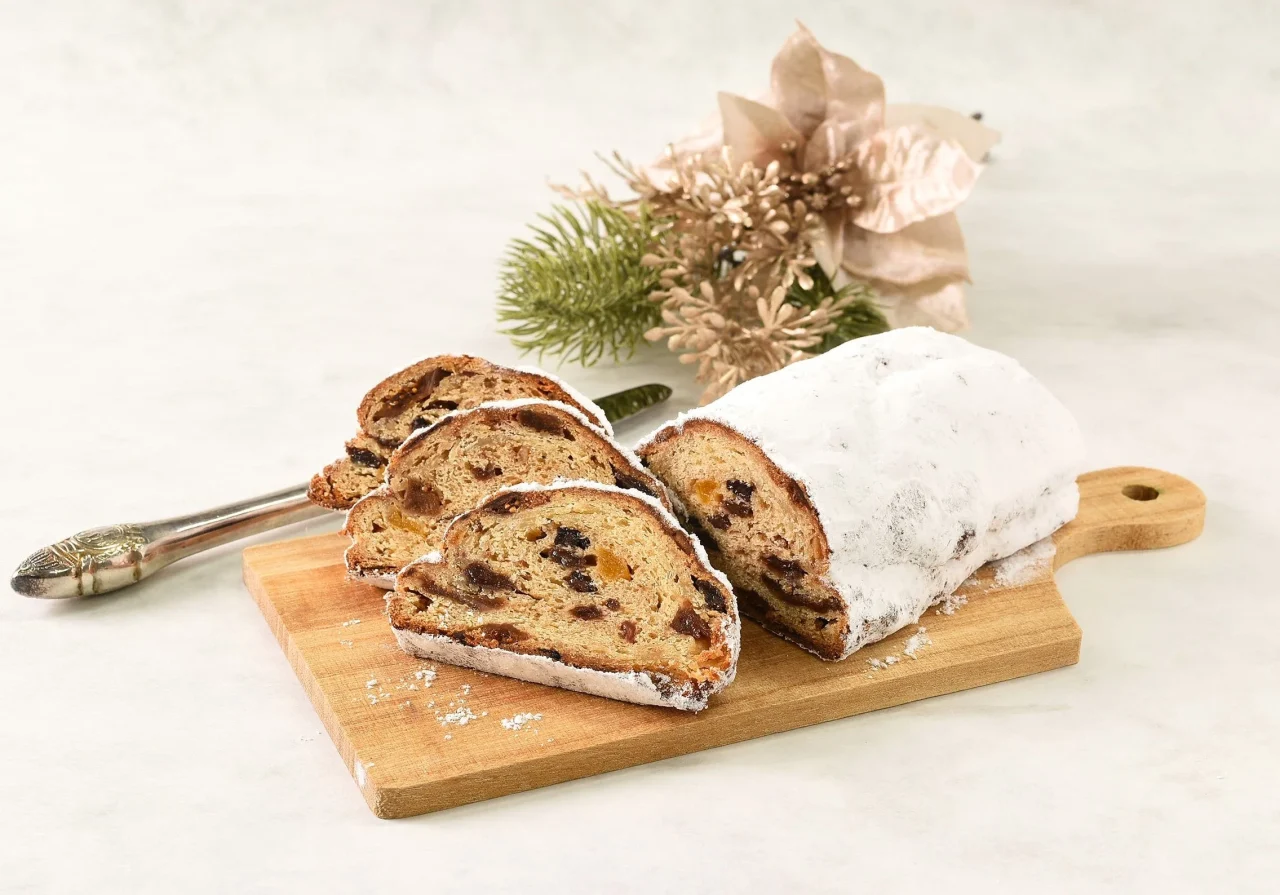 クリスマスプレミアムシュトーレン。粉砂糖をまとい、数切れにカットして木製ボードに並ぶ