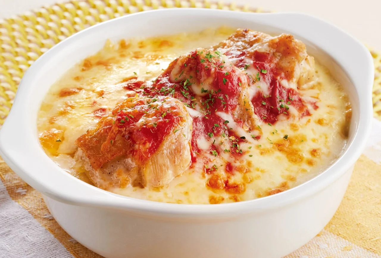 白い耐熱皿に入ったチキンドリア。チーズとトマトソースが焼かれている