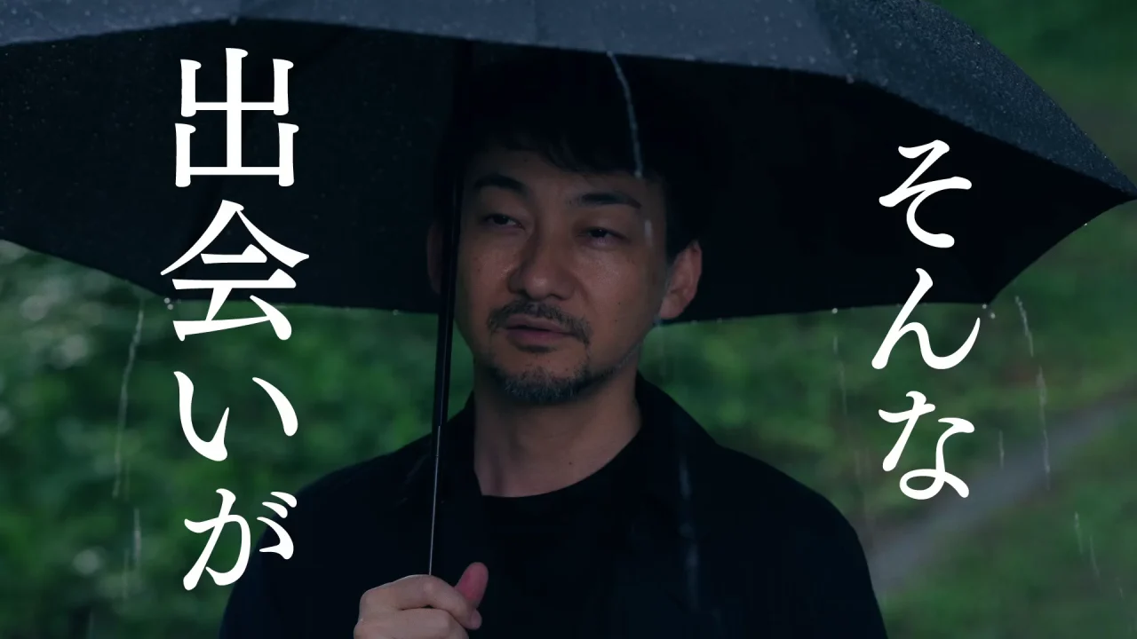 雨の中、黒い傘を差す男性。「そんな出会いが」の白い縦文字入り