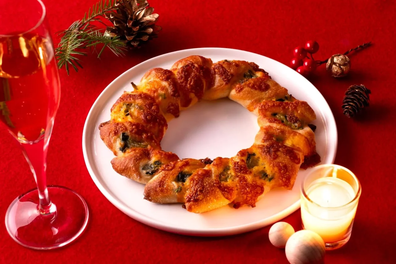 白い皿にのったリース状のスピナッチリング。チーズ焼き色とシャンパン
