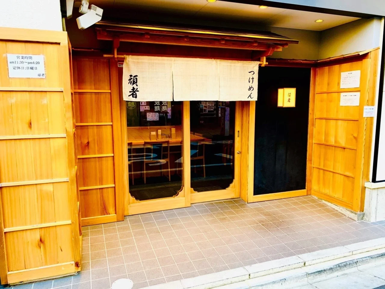 頑者の店舗外観。木製の引き戸と暖簾のある入口