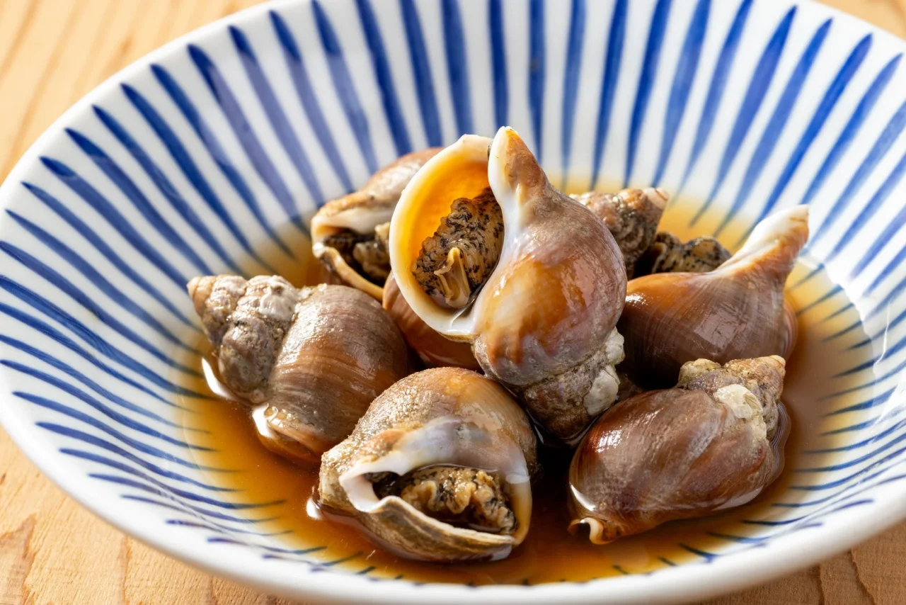 青い縞模様の器に盛られた磯つぶ貝の旨煮