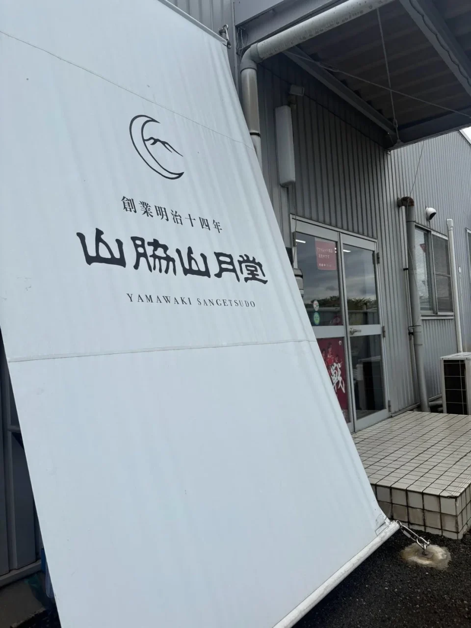 山脇山月堂の店舗外観と白い看板。創業明治十四年のロゴ入り