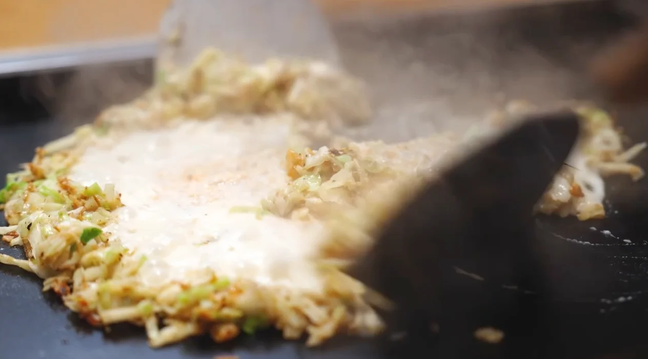 鉄板の上でヘラを使い焼かれるもんじゃ焼き