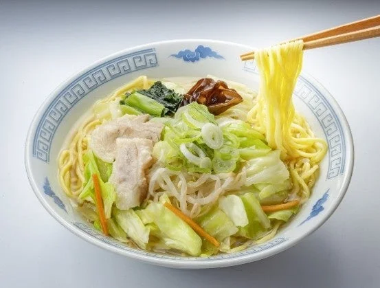 1/2日分野菜盛り塩タンメン。青い模様の丼にキャベツやもやしが盛られ、箸で麺を持ち上げる