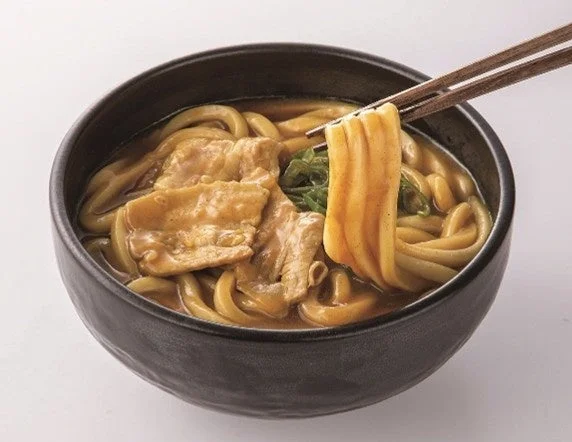 スパイス香るコク旨カレーうどん。黒い丼に豚肉入りで、箸が麺を持ち上げている