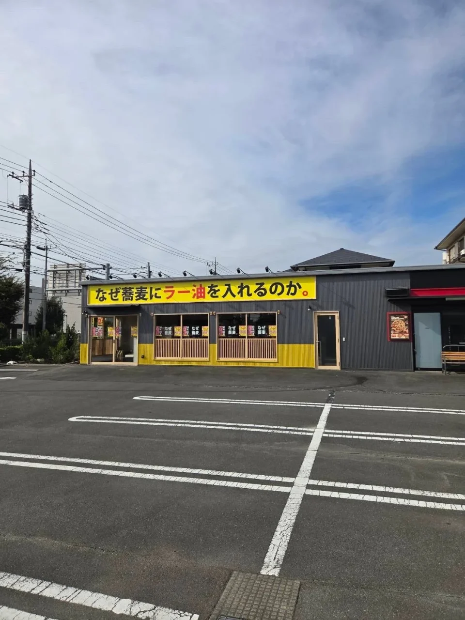 黄色い看板が目立つ「なぜ蕎麦にラー油を入れるのか。」のロードサイド店舗外観