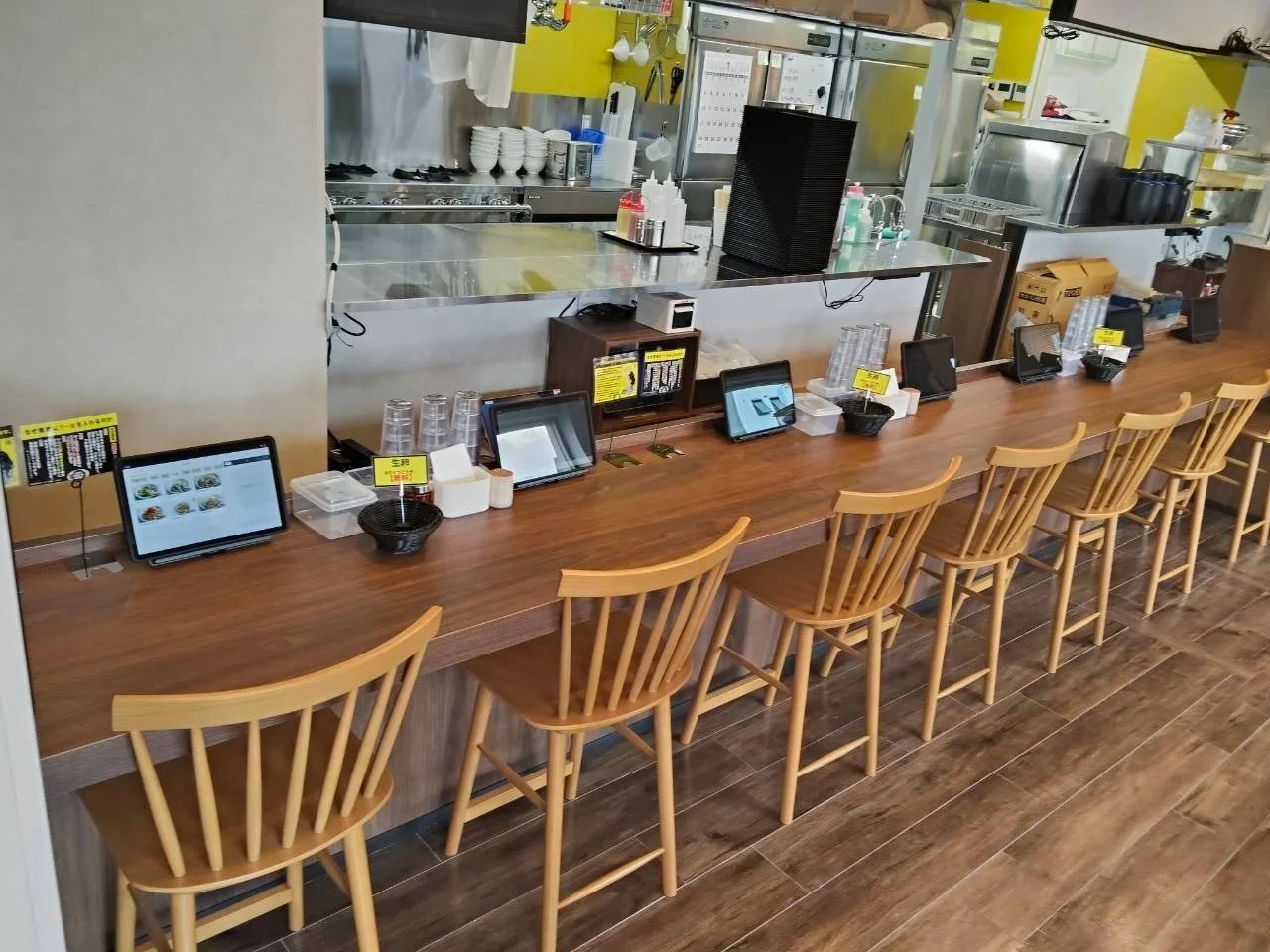 カウンター席。木目の長いカウンターに木製の椅子が並ぶ店内