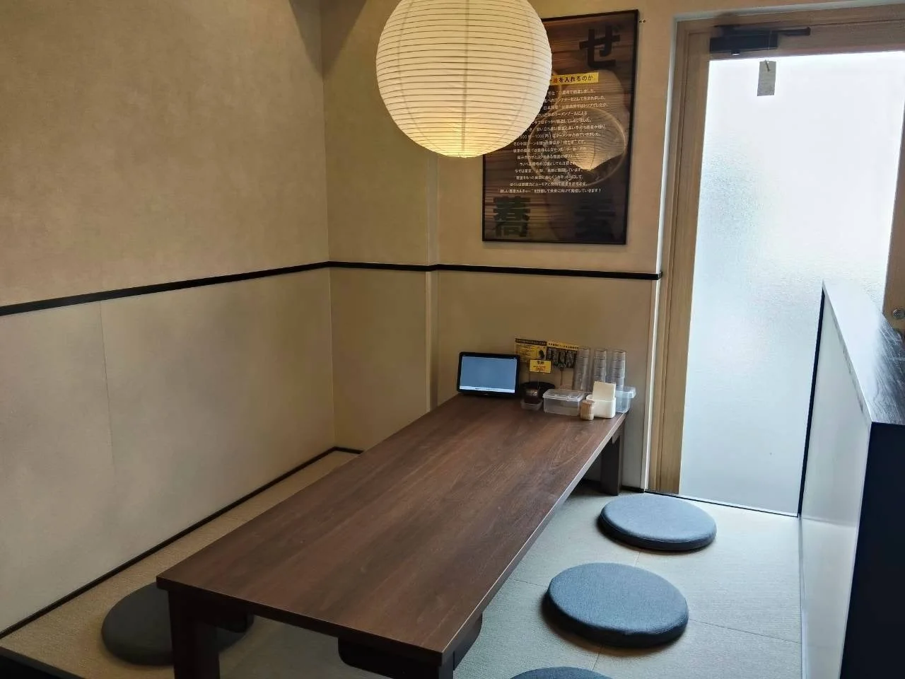 小上がり席。木製の座卓と丸い座布団、白い提灯が見える店内