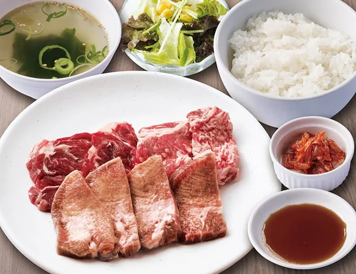 熟成タンとカルビ焼肉定食。肉の皿にご飯、スープ、サラダ、キムチ、タレ