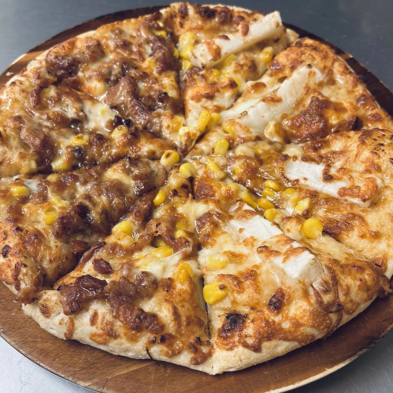 照焼チキンとお餅の照りダレハーフ。コーンとチーズがのった焼き上がりのピザ