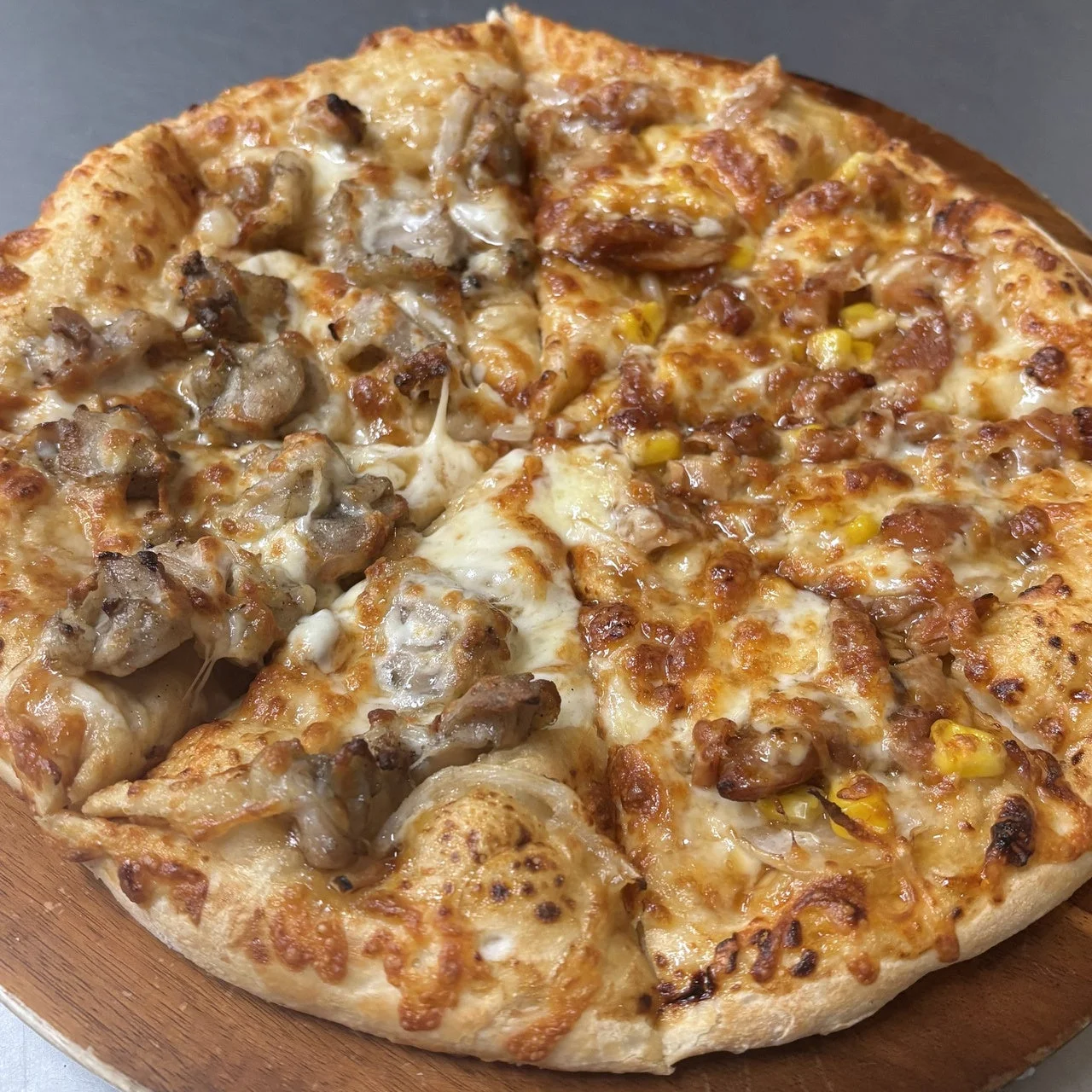 鶏ハラミとチキンの照りダレハーフ。チーズとコーンがのった丸いピザ
