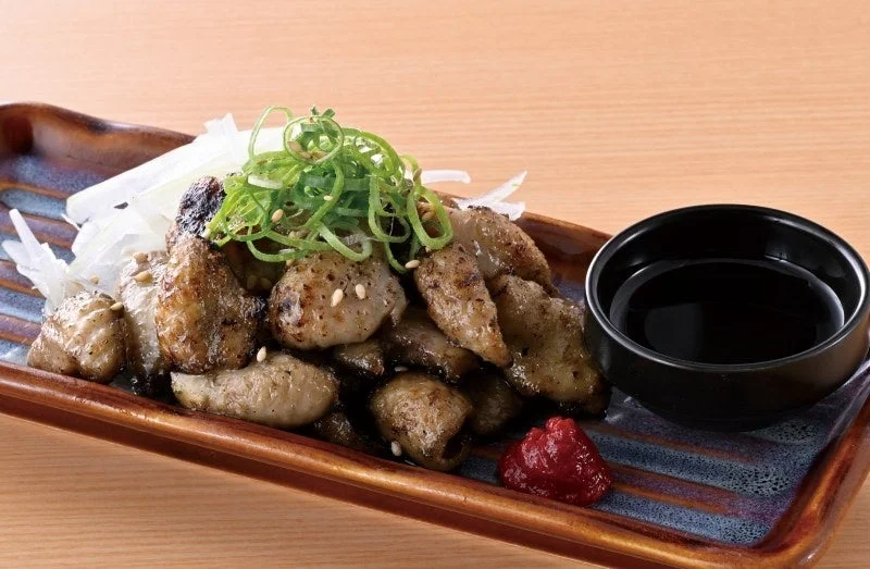 炙り鶏皮ぽん酢。ネギと大根を添えた焼き目の付いた鶏皮と、ぽん酢の小鉢