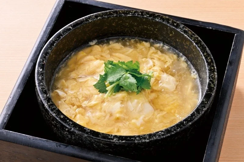 手作り豆富の比叡湯葉あんかけ。黒い石の器に三つ葉をのせた料理