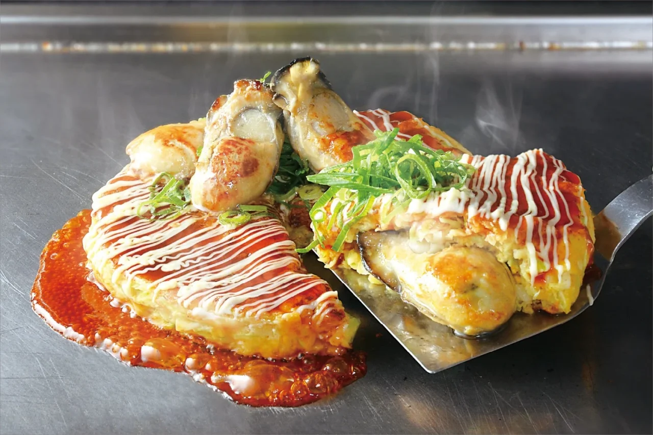 鉄板上の牡蠣のお好み焼き。大粒牡蠣とマヨネーズ、ねぎがのる