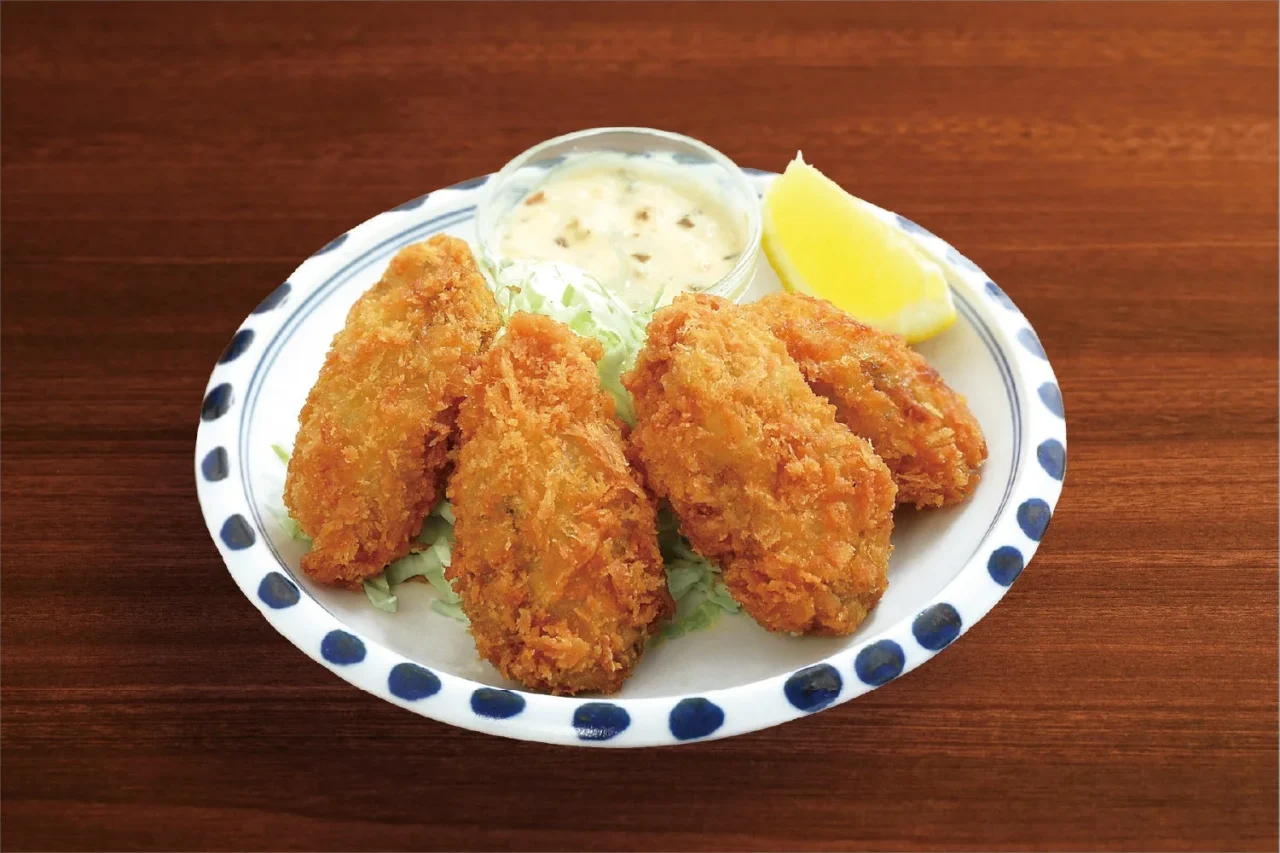 広島県産 牡蠣フライ。レモンとタルタル風ソースを添えた皿