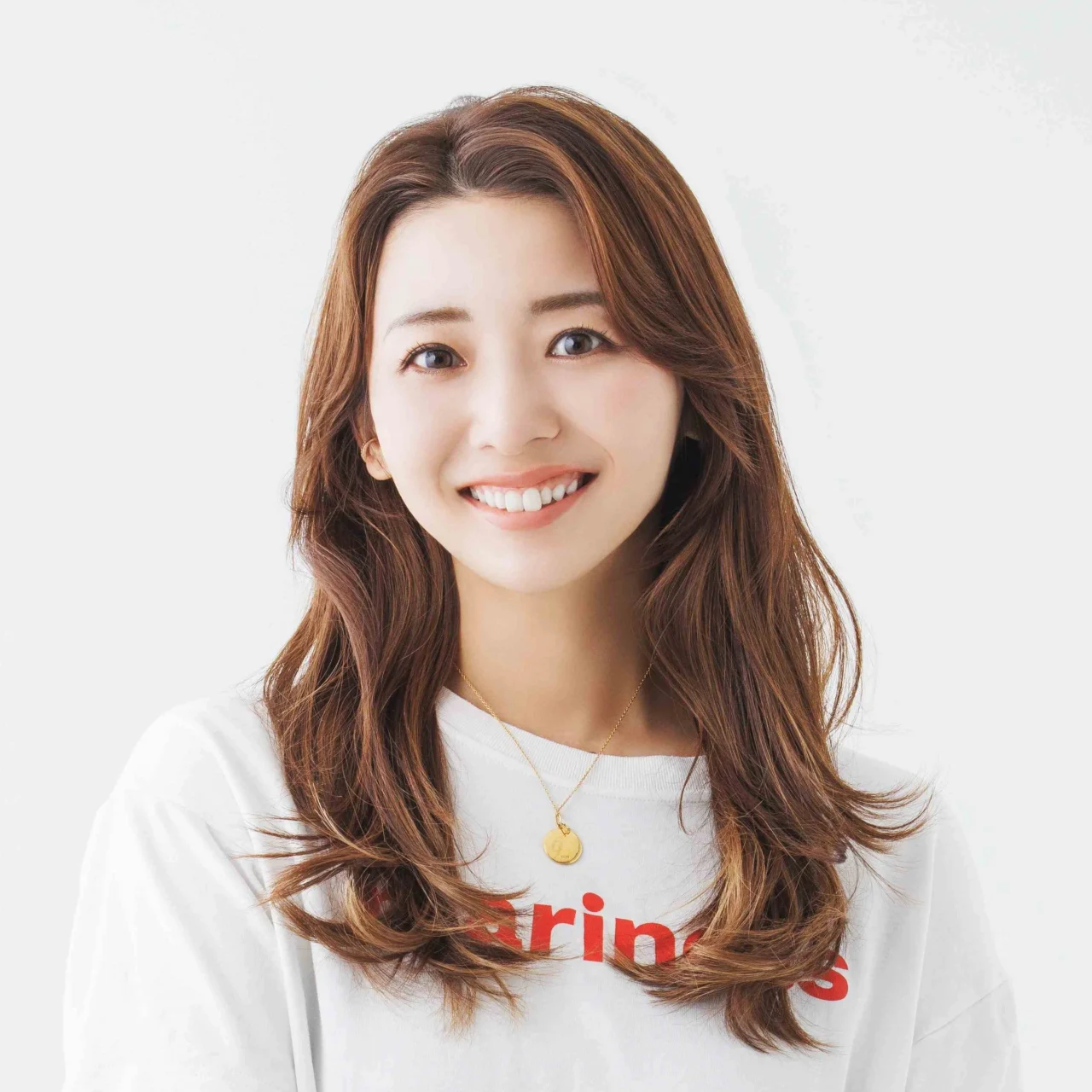 竹脇まりな氏の笑顔のポートレート。白いTシャツに茶色のロングヘア