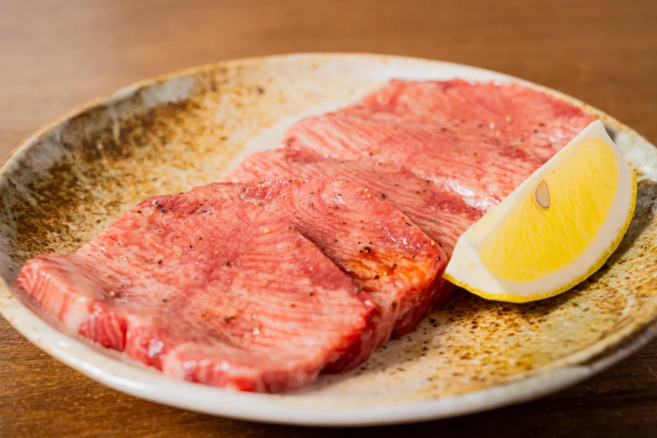 上たん。陶器の皿に盛られた薄切りの肉とレモン
