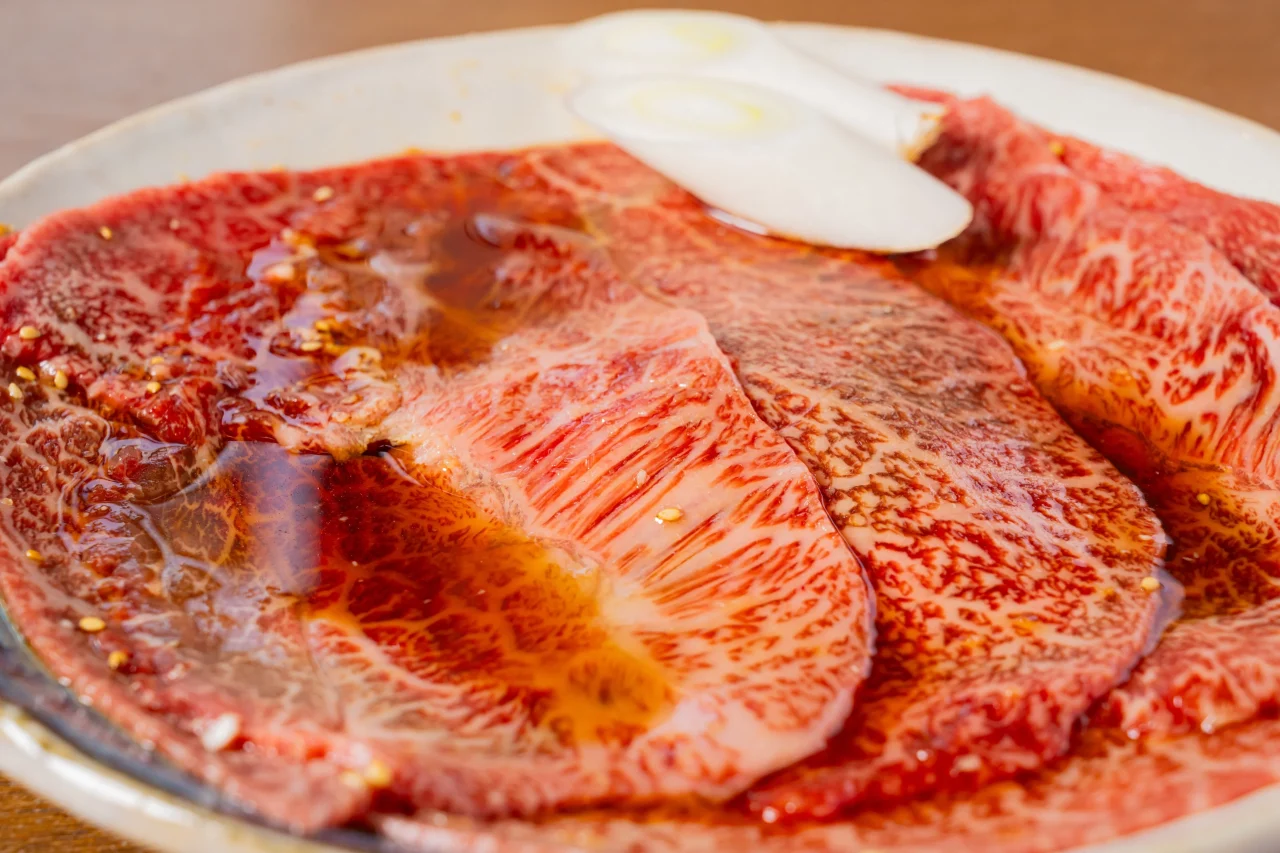 やきしゃぶ4種盛 皿に盛られた薄切りの赤身肉とたれ、白ねぎ