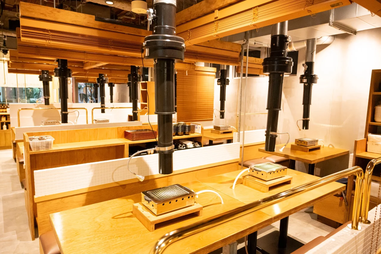 浜松町 たれ焼肉のんき 裏の店内。無煙ロースターと排気ダクトが並ぶ木製テーブル席