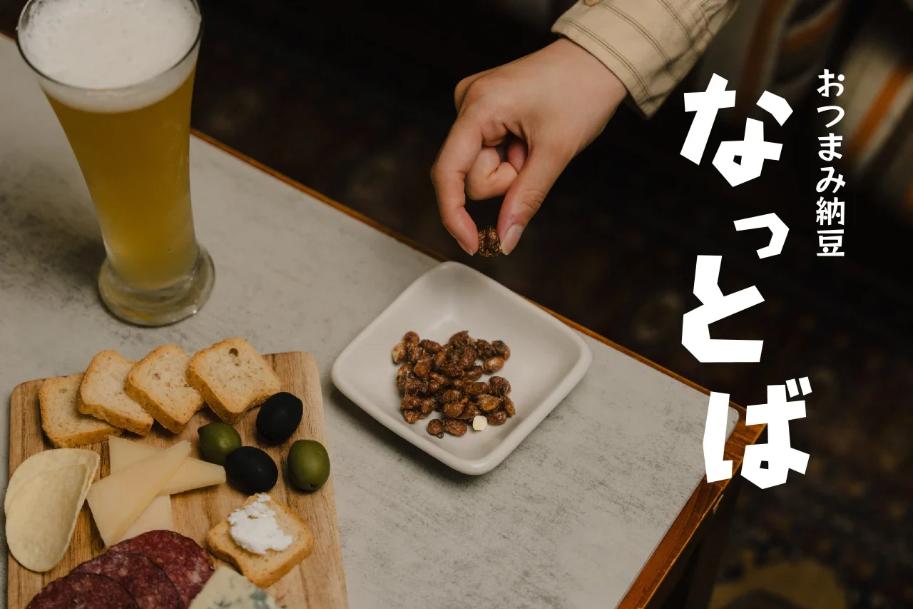 ビールとおつまみ納豆「なっとば」を白い小皿から手でつまむ様子
