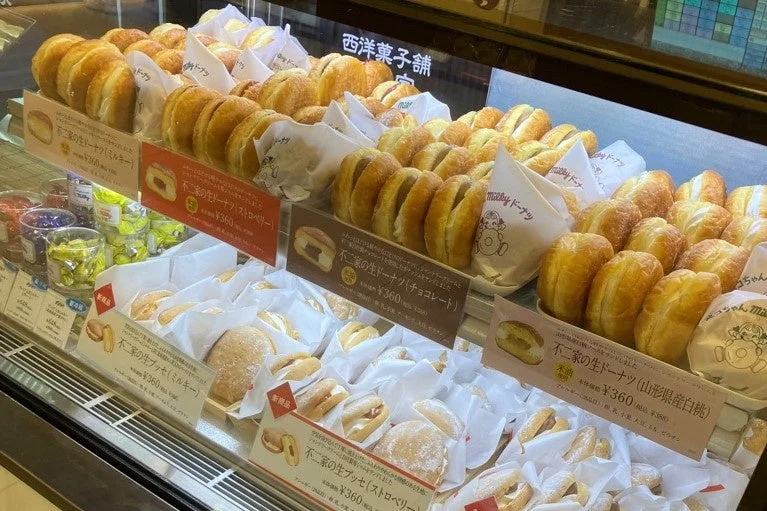 洋菓子店のショーケースに並ぶ不二家の生ドーナツと価格札