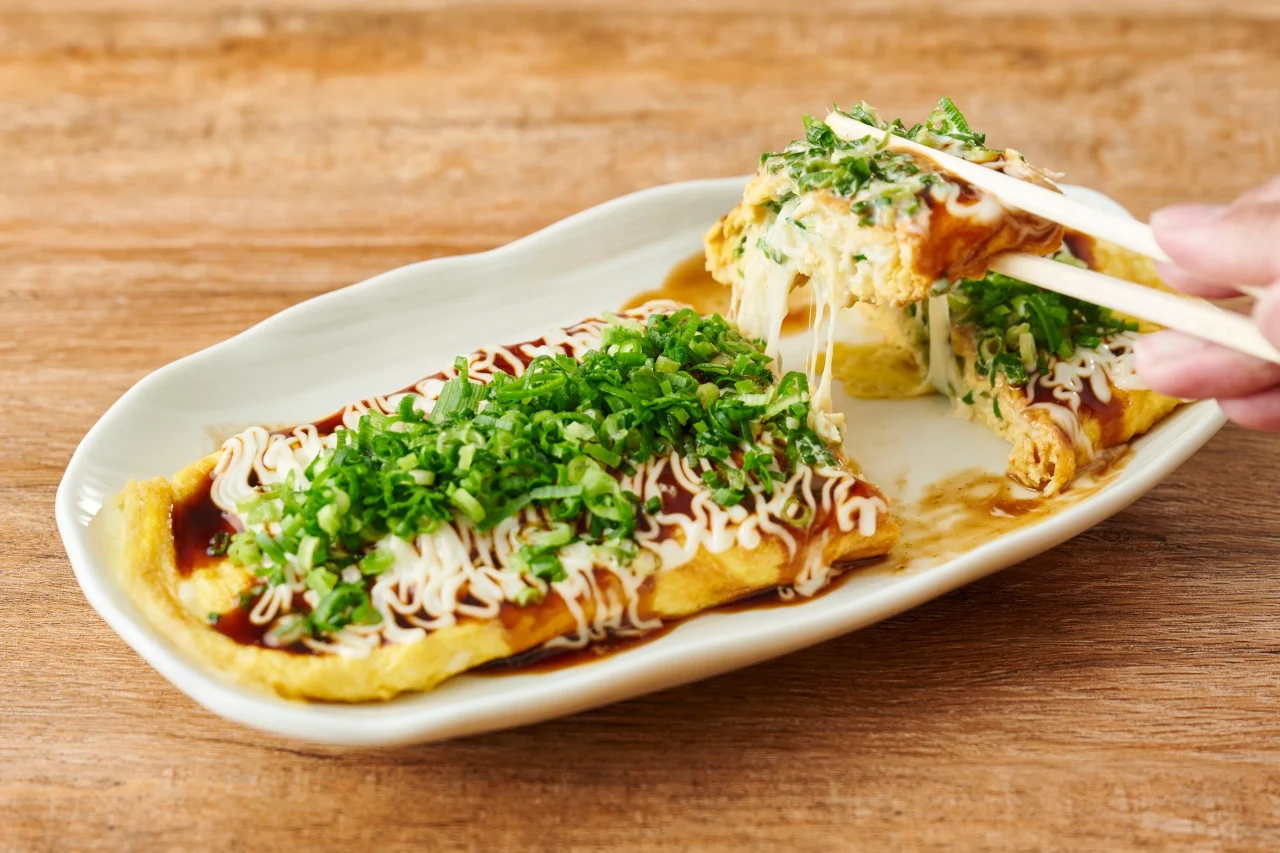 葱まみれチー平焼き。ねぎとマヨネーズがかかった卵焼きを箸で持ち上げた様子