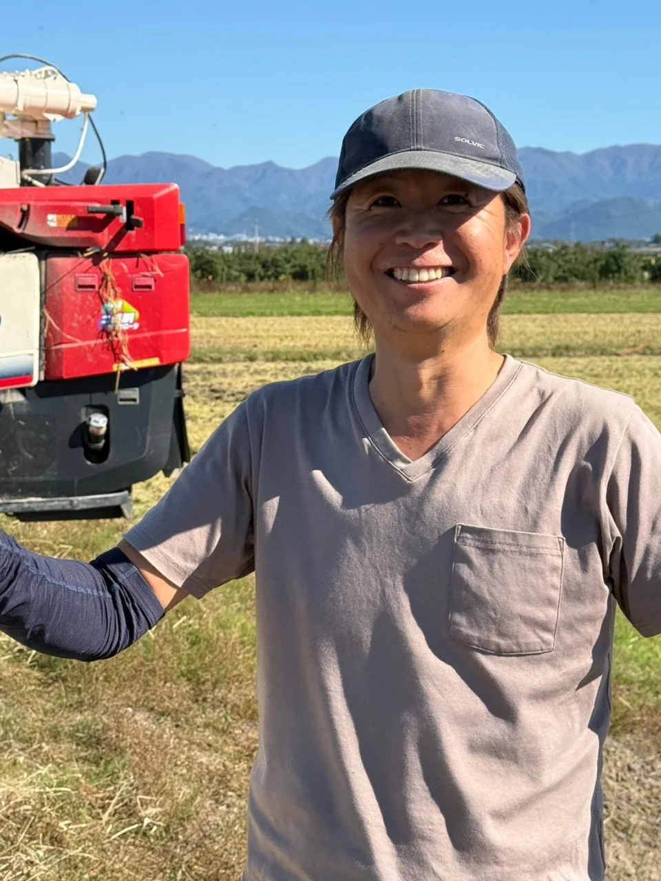 鎌上正樹さん。キャップとグレーのTシャツ姿で笑顔の生産者