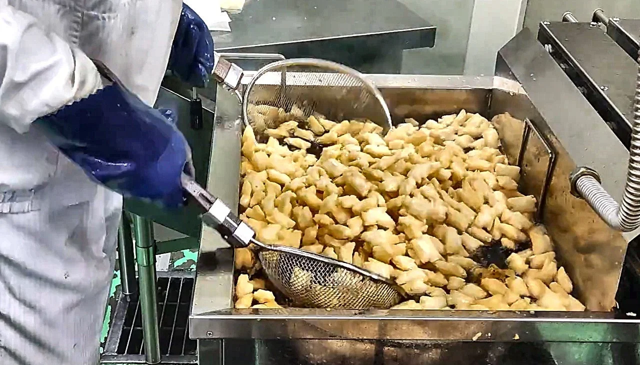 新米手揚げおかきを工場で網ですくい揚げる作業の様子