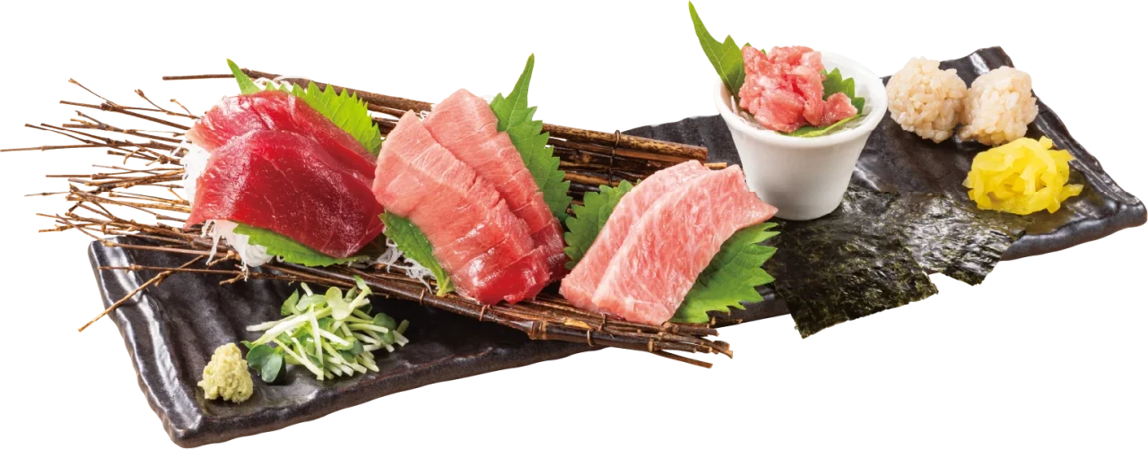 黒い皿に盛られた刺身3種と小鉢、海苔、わさび、黄色い漬物