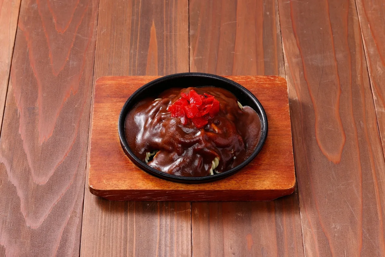 アパ社長カレー焼ラーメン。鉄板皿にカレーがかかり紅しょうが添え