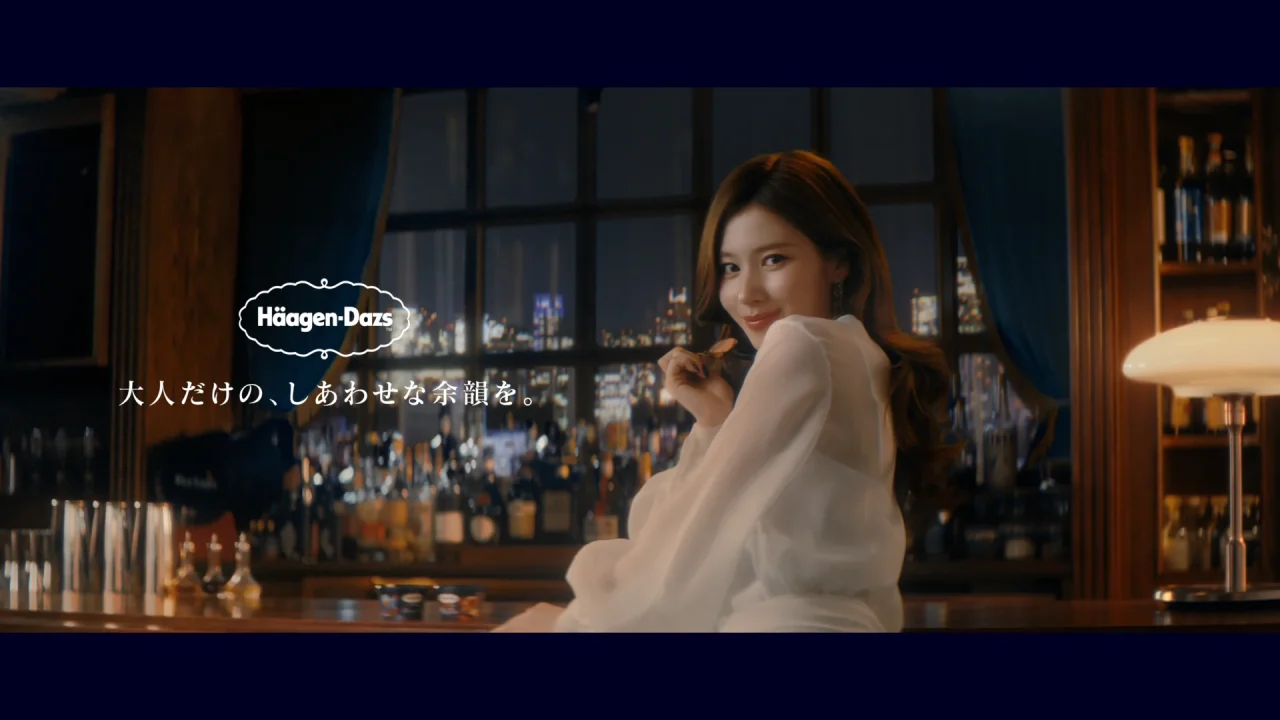 WEB CM「しあわせな余韻」篇のバーカウンターに座り微笑む白いブラウスの女性