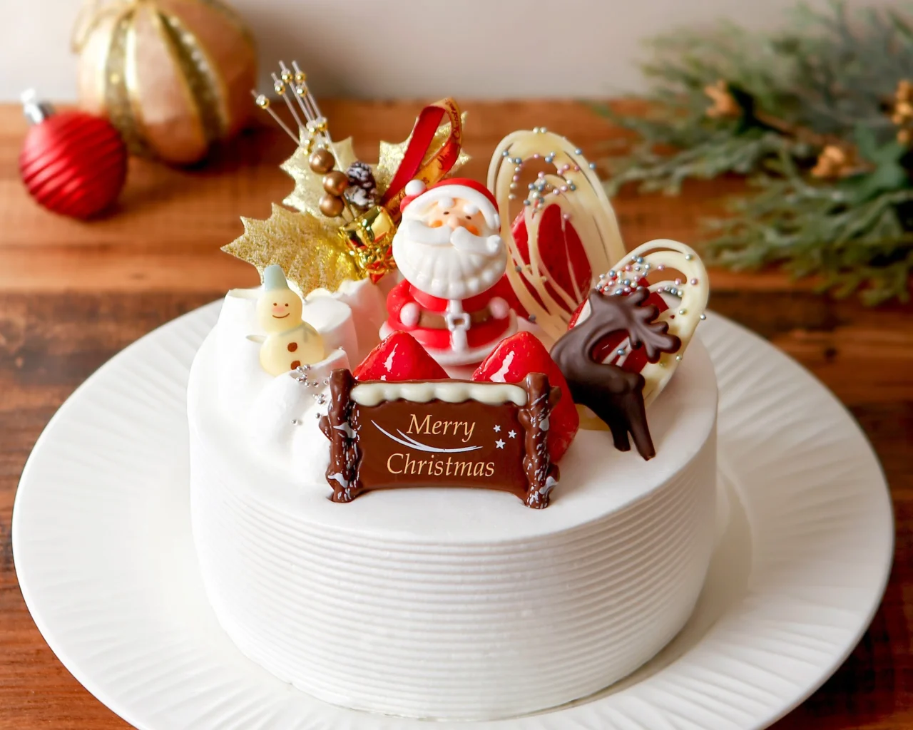 サンタをのせたデコレーション。Merry Christmasプレート付きの白い丸型ケーキ