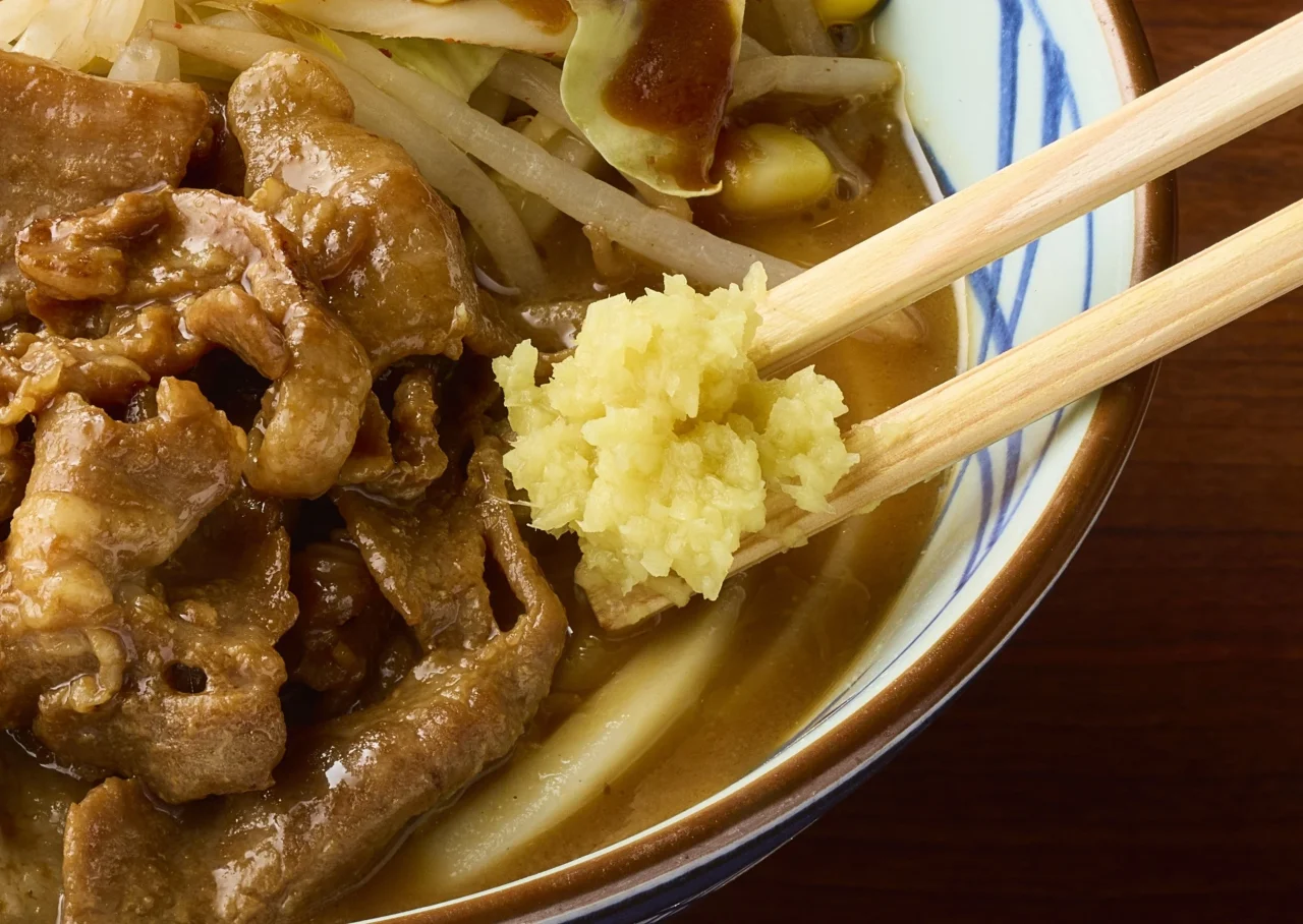 おろししょうがを箸で持ち上げた、豚肉と野菜入り味噌だしうどん