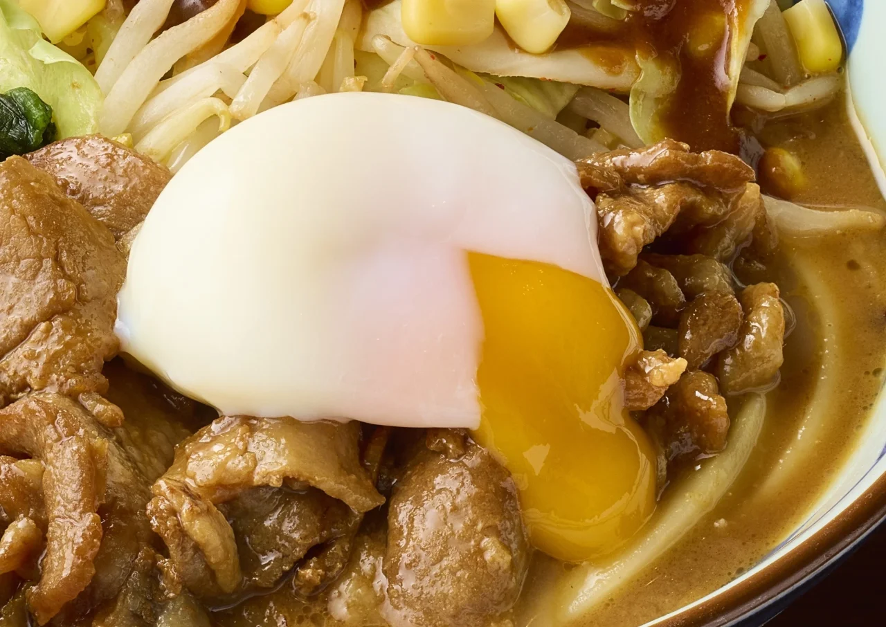 温泉玉子をのせた濃厚味噌だしうどん。黄身がとろりと流れ出ている