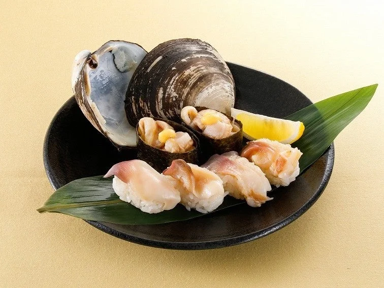 まるごと北寄貝にぎり。貝殻と握り、軍艦、レモンを黒皿に盛り付け