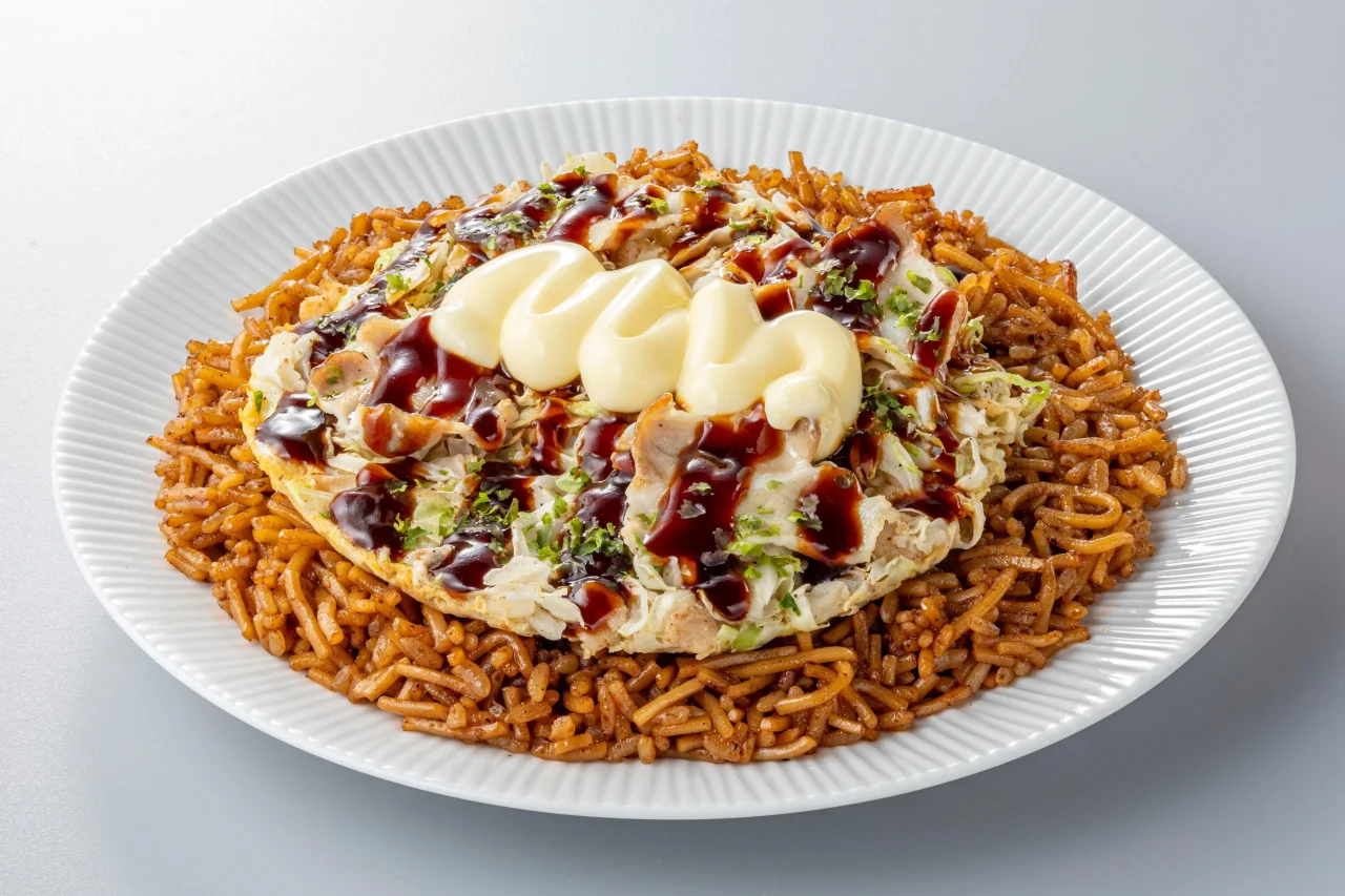 白い皿に盛られた、ソースとマヨネーズがのった具材と茶色い炒め飯の料理